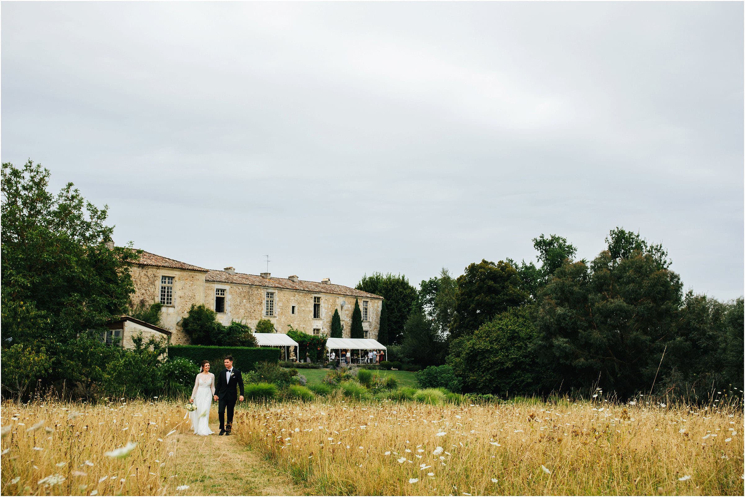 a destination wedding photographer follows a bride and groom in a field