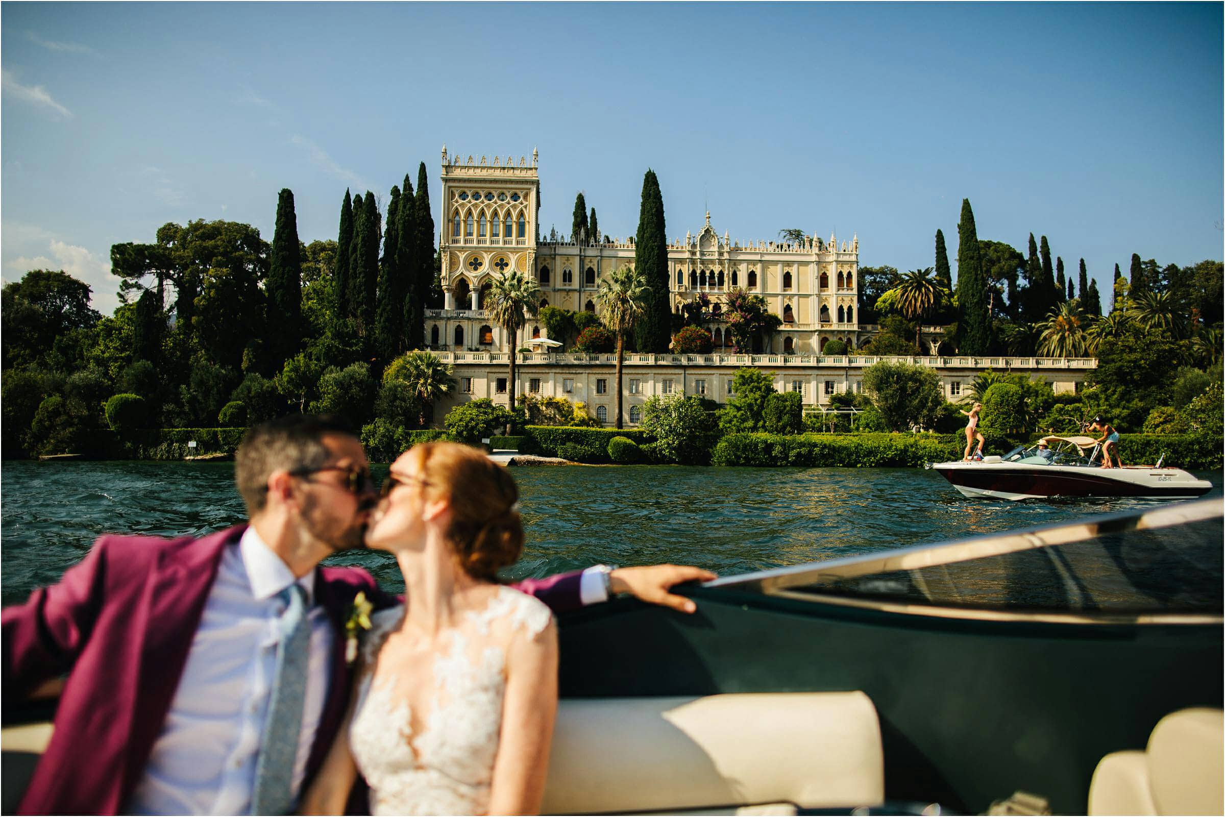 a bride and groom kissing on a boat in lake garda italy