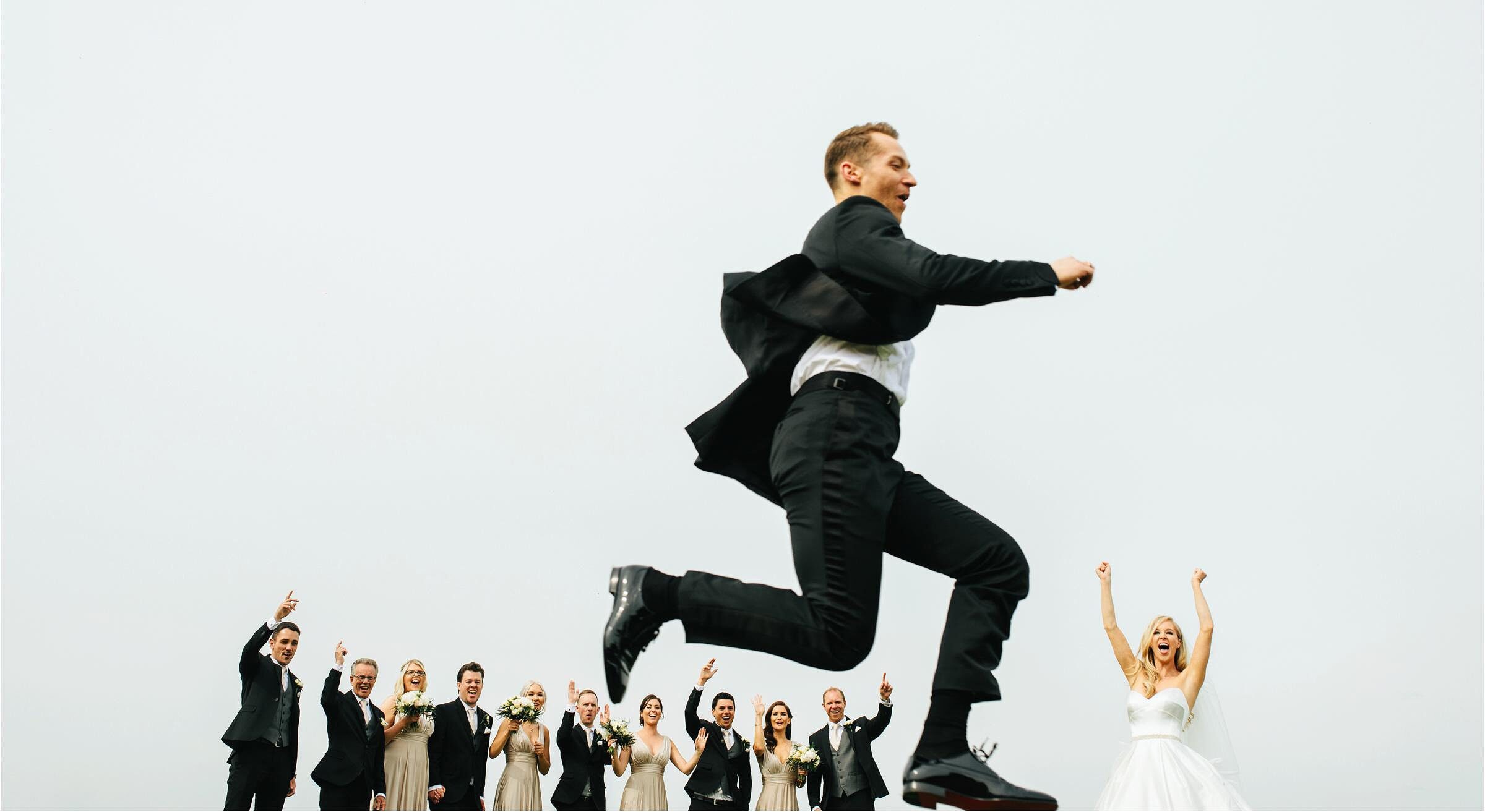 a picture of a groom jumping through the air at his uk wedding