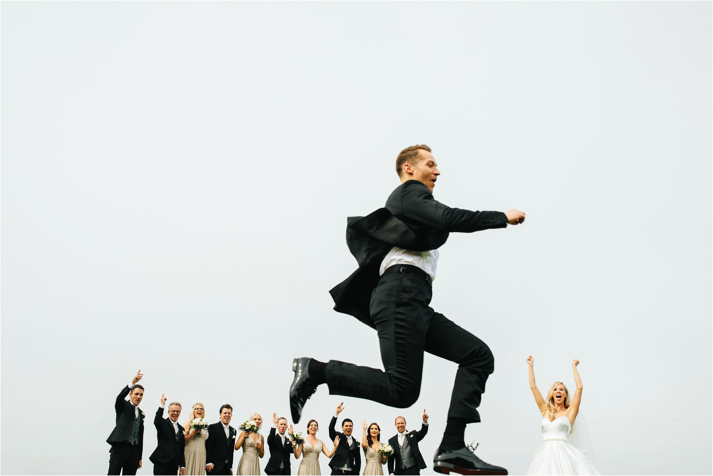 a picture of a groom jumping through the air at his uk wedding